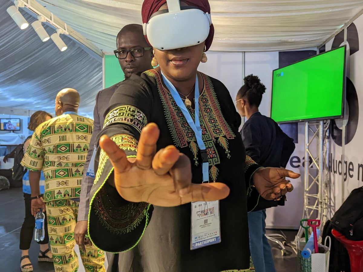 Une participante découvre l'expérience de réalité virtuelle sur l'assainissement, guidée par Mansour Fall (World Water Summit, Nigeria)